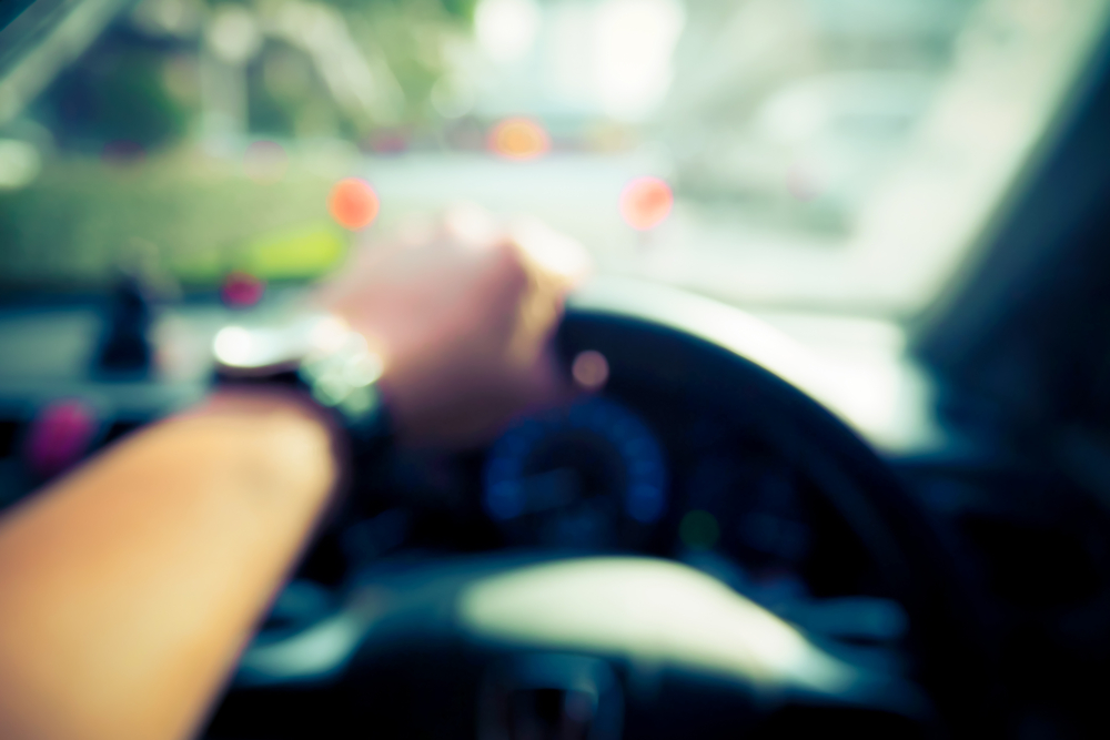 hands driving car steering wheel, blurred