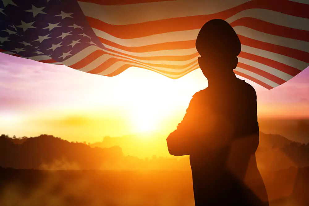 Silhouette of Soldier on the United States flag in sunset for Veterans Day