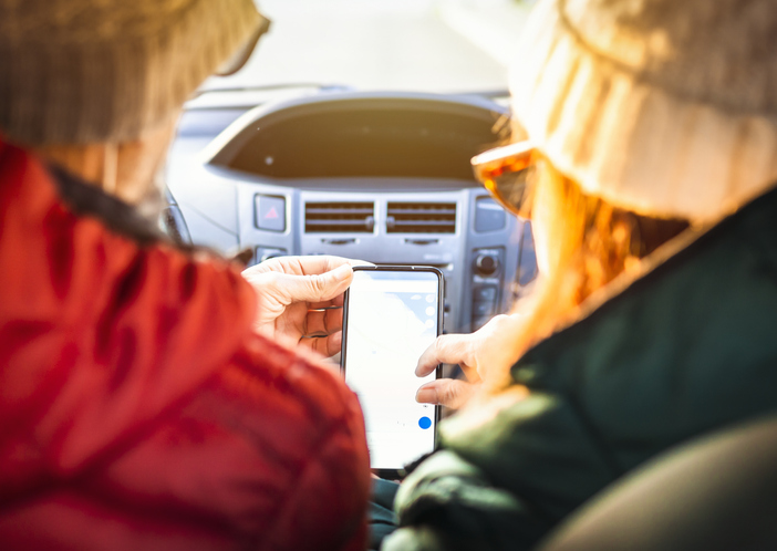 Two people looking at their phones in a car.